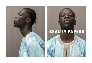Two portraits of a Black man with cornrows wearing a light blue embroidered tunic and silver hoop earrings against a neutral grey background