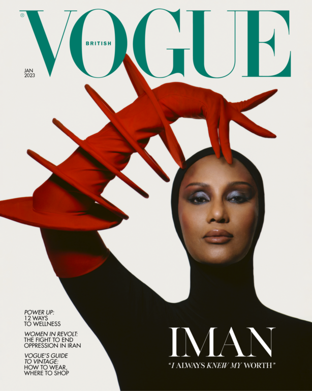 Model Iman wearing a black hood and dramatic red sculptural gloves against a solid white background for a magazine cover