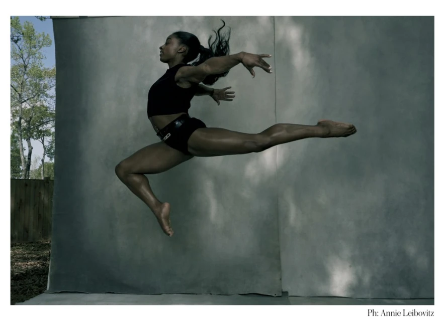 Athletic Black woman leaps mid-air against a muted grey background, demonstrating strength and grace in sportswear with natural lighting.