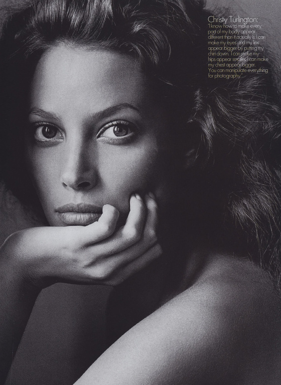 Striking black and white portrait of Christy Turlington with dark wavy hair, her chin resting on her hand in a classic pose.