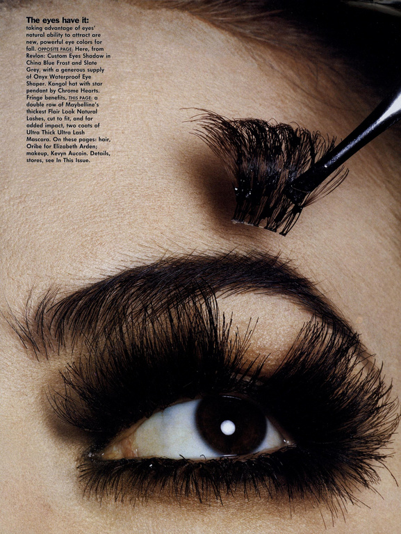 Close-up of a person's eye with very long, dramatic false eyelashes being applied with a cosmetic brush for a beauty campaign.