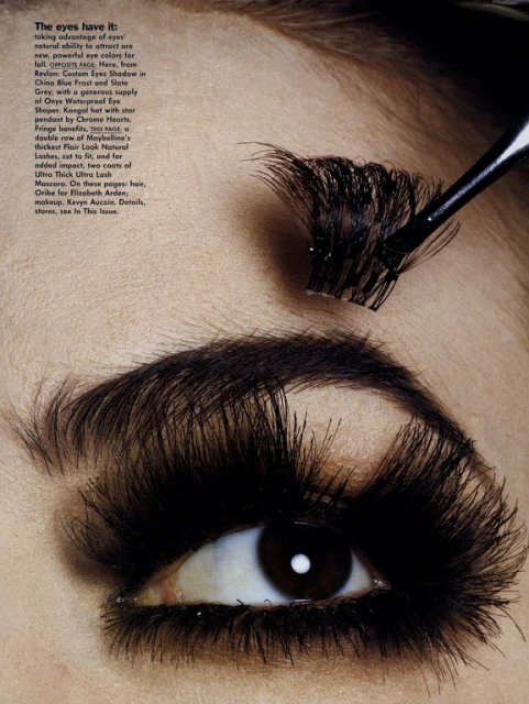 Close-up of a person's eye with very long, dramatic false eyelashes being applied with a cosmetic brush for a beauty campaign.