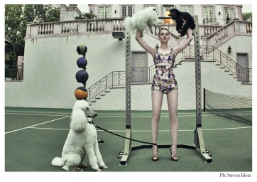 Model holding two small dogs up in a gym rack on a tennis court styled by Phyllis Posnick