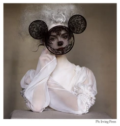 Model wearing a white sheer blouse and a black lace mask shaped like mouse ears, styled by Phyllis Posnick.