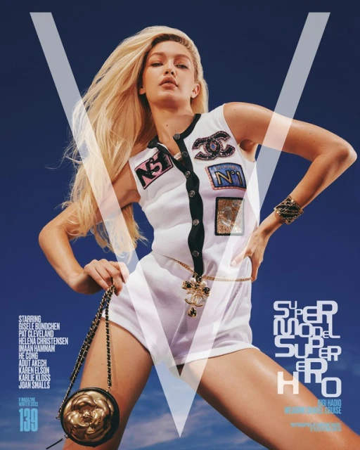 Magazine cover featuring Gigi Hadid wearing a Chanel-themed white romper, posing in front of a blue backdrop with a large white 'V' overlay.