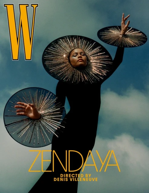 Zendaya on magazine cover wearing avant-garde black dress and sun-like headpiece against a cloudy sky background in a dramatic pose.