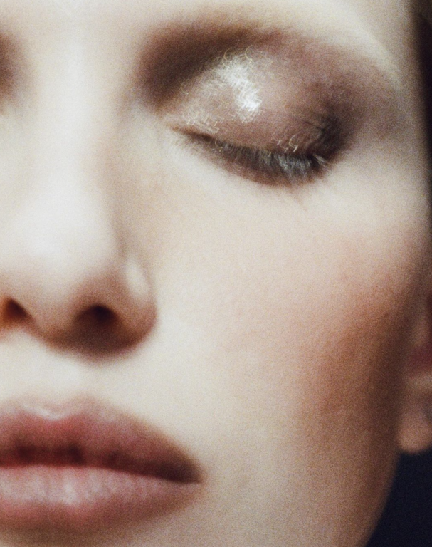 Close-up of a woman's face with eyes closed, showcasing a soft, blurred aesthetic and subtle makeup for a serene beauty image.