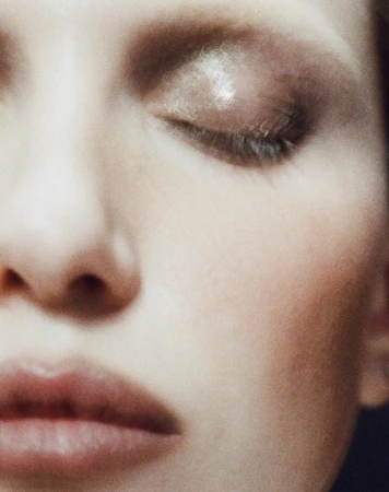 Close-up of a woman's face with eyes closed, showcasing a soft, blurred aesthetic and subtle makeup for a serene beauty image.