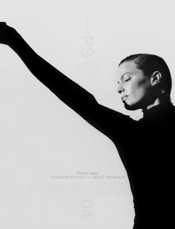 Black and white portrait of adult female with short hair looking down with arm raised against a stark white background in a photo studio.
