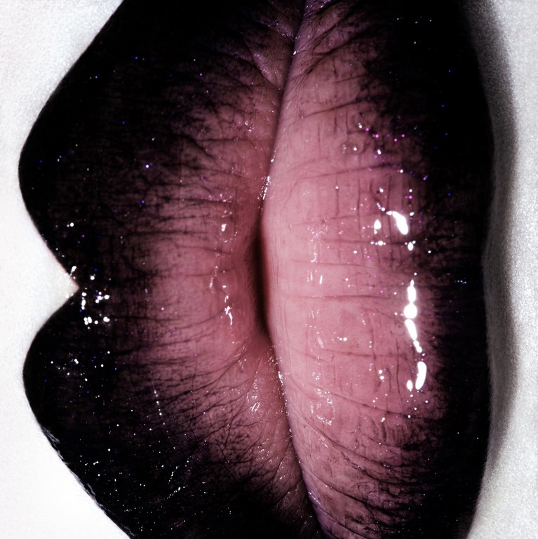 Extreme close-up of human lips featuring dark ombre lipstick and glossy texture, set against a bright white background.
