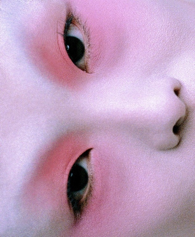 Close-up of a face with eyes open and pink blush. Minimalist beauty shot emphasizing skin texture, eyes, and subtle makeup application.