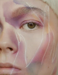 Close-up portrait of a model with artistic makeup, featuring purple washes and delicate white line art by make-up artist Jezz Hill.