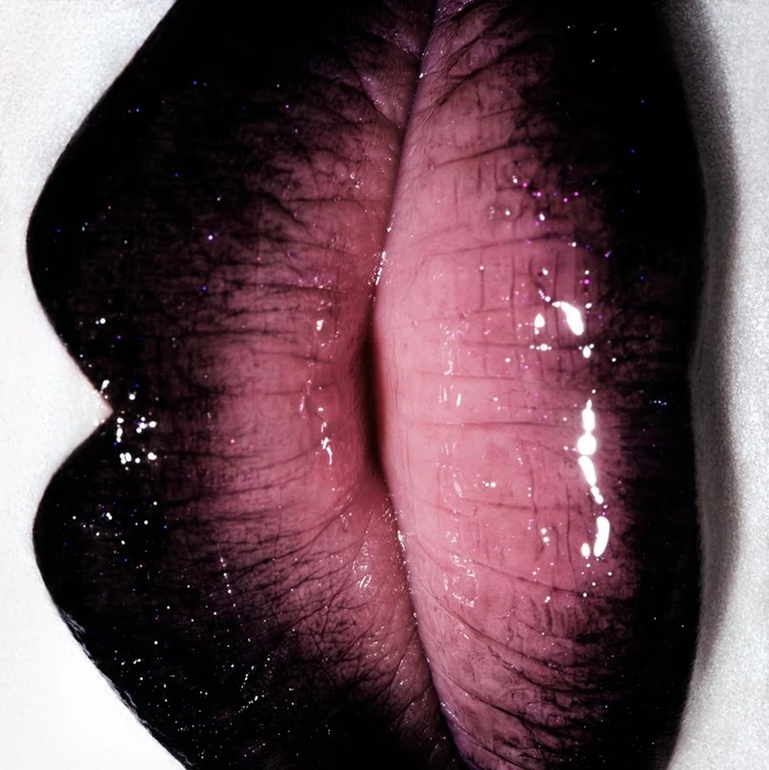 Extreme close-up macro view of glossy dark lips with purple glitter highlights and visible lip lines by Jezz Hill