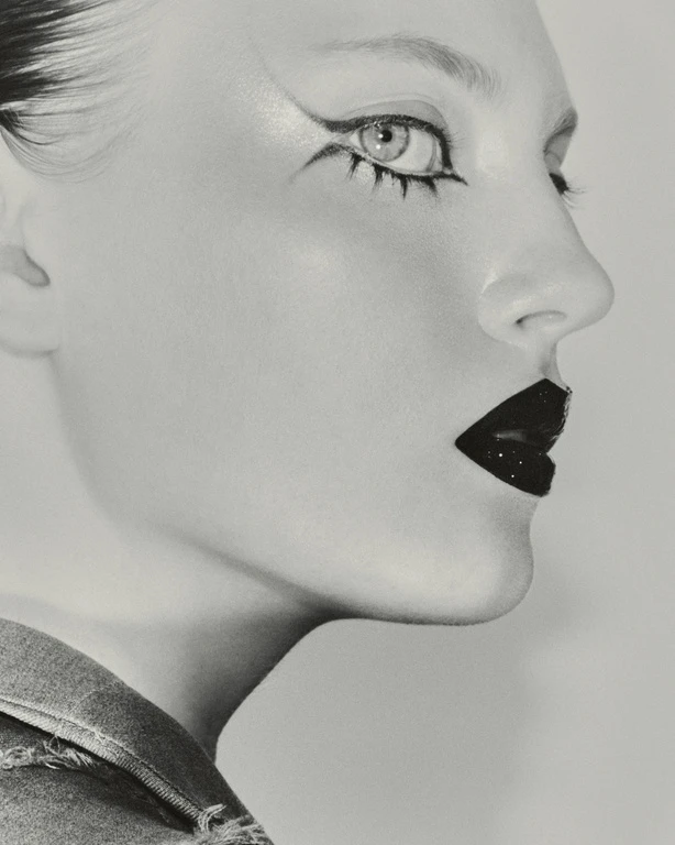 Close-up profile of a model with sharp black graphic eyeliner and glossy dark lips styled by Grace Sinnott