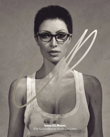 Black and white portrait of Kim Kardashian wearing glasses and a tank top for a magazine cover, shot in a photo studio.