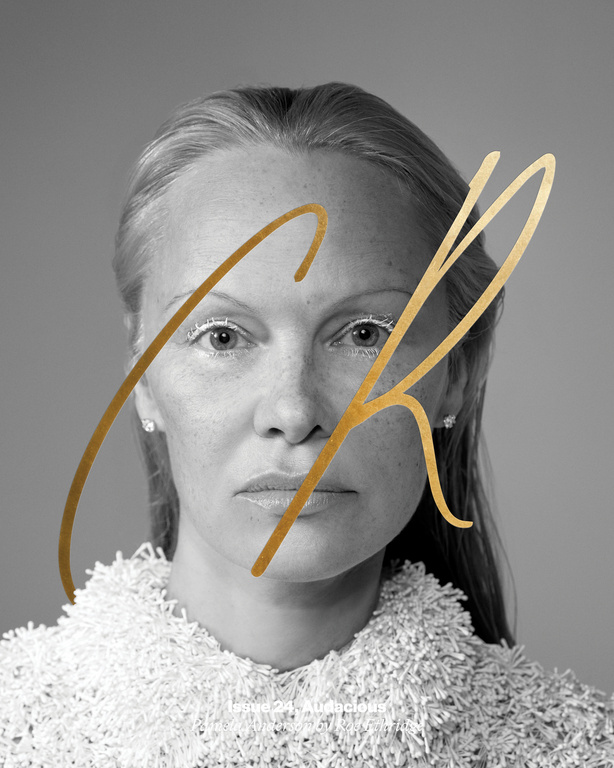 Black and white portrait of woman with fair skin, wearing a textured white top against a grey background with golden accents.