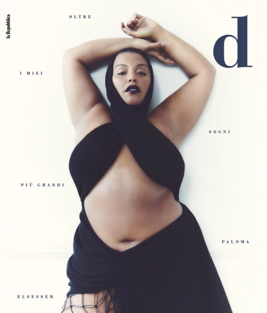 Paloma Elsesser poses for magazine cover, wearing black wrap dress and head covering against a neutral background.