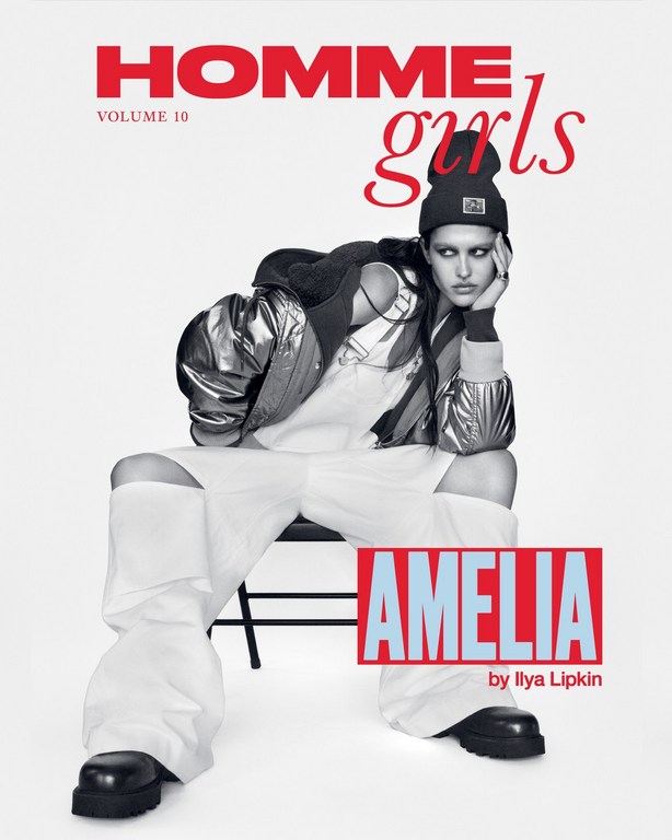 Fashion magazine cover featuring a female model in a silver jacket, white pants, and black beanie, seated against a white backdrop. The cover includes red and blue text.