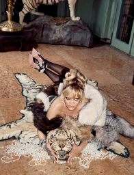 Rihanna posing on a patterned rug with a tiger pelt, styled by hair stylist Jackson Heller in an opulent interior setting
