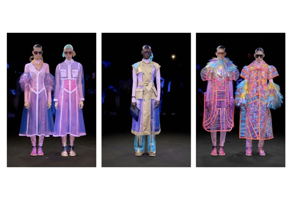 Fashion runway presentation featuring three models wearing uniquely designed transparent coats in a dark indoor setting with blue lighting.