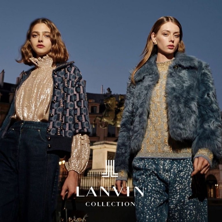 Two fashion models showcase Lanvin Collection apparel outdoors. One wears a sequin top and patterned jacket, while the other sports a fur coat.