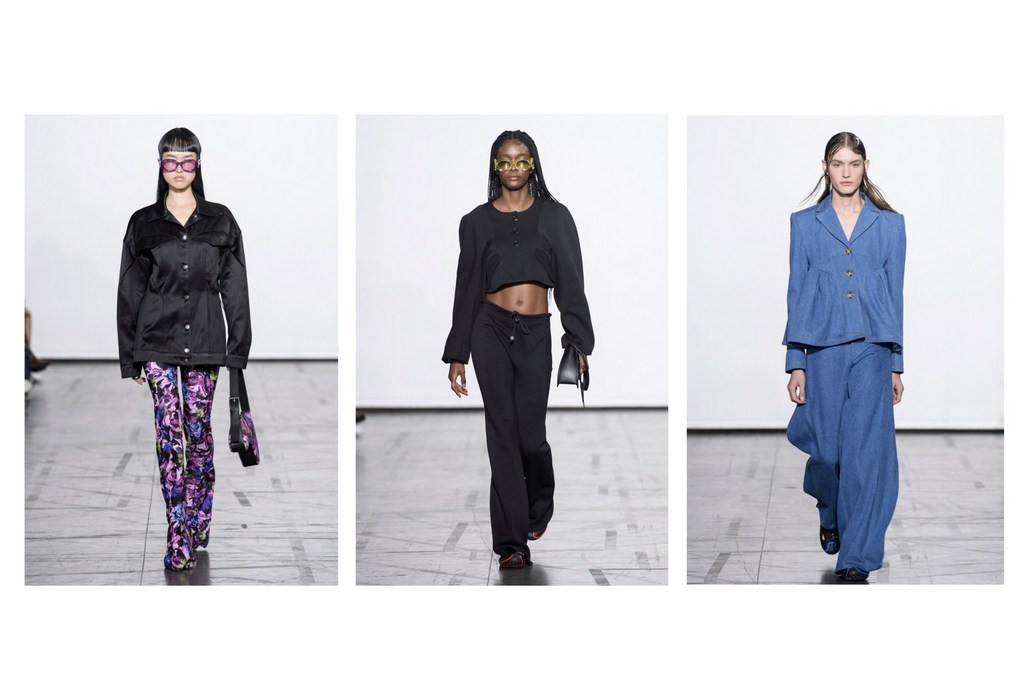 Three fashion models showcase runway looks: a black jacket with floral pants, a cropped black top and pants, and a blue denim suit.