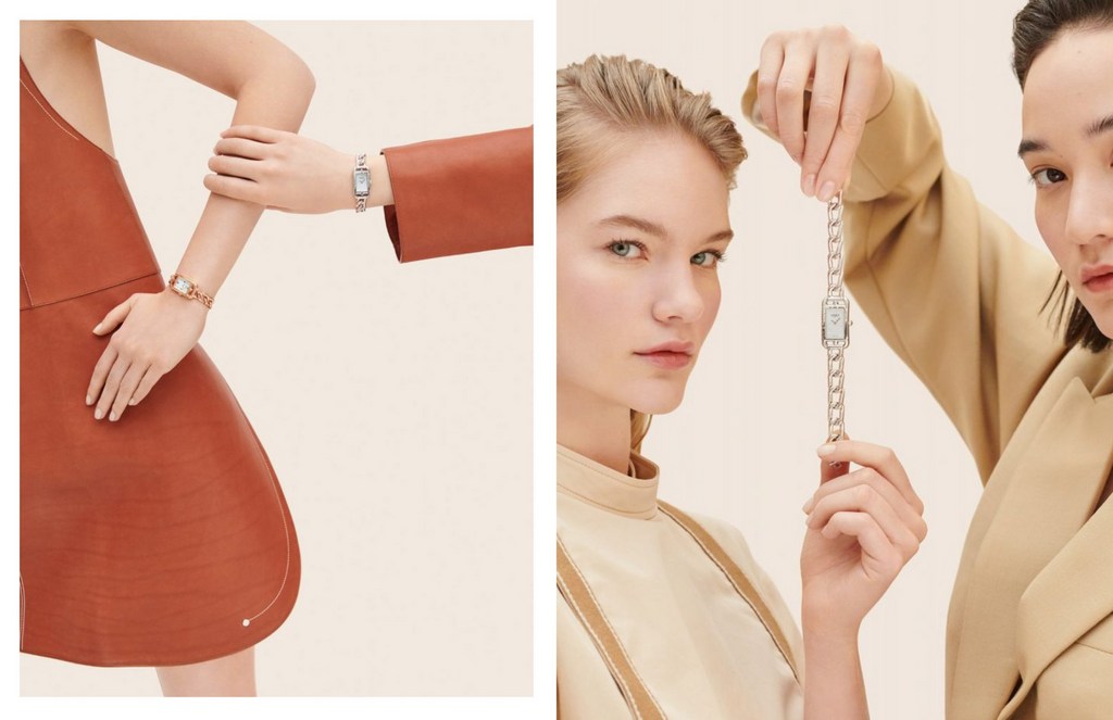 Two women showcase luxury wristwatches with silver chain bands against a neutral backdrop in a studio setting, promoting elegance.