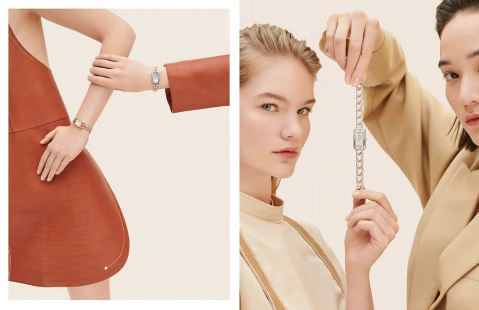 Two women showcase luxury wristwatches with silver chain bands against a neutral backdrop in a studio setting, promoting elegance.