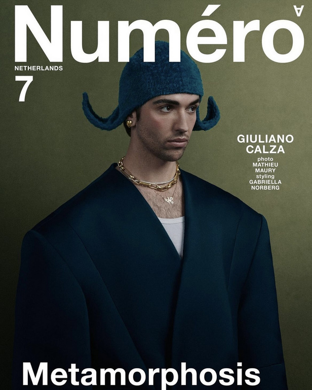 Numero Netherlands magazine cover featuring an adult male model in an oversized blue jacket and matching knit cap, against an olive-green backdrop.