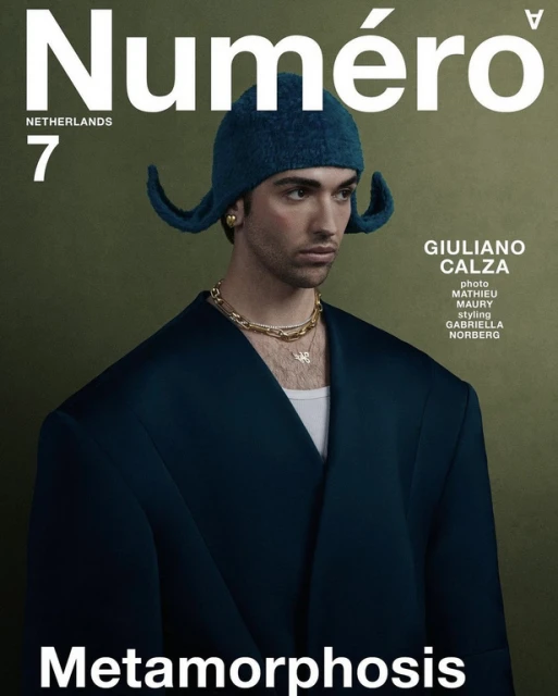 Numero Netherlands magazine cover featuring an adult male model in an oversized blue jacket and matching knit cap, against an olive-green backdrop.