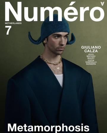 Numero Netherlands magazine cover featuring an adult male model in an oversized blue jacket and matching knit cap, against an olive-green backdrop.
