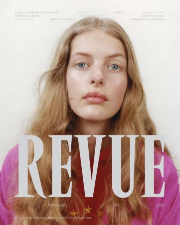Fashion magazine cover featuring a young woman with blond wavy hair wearing a pink top, posing in front of a white background.