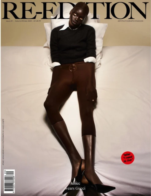 Magazine cover featuring Athiec wearing a black sweater, brown cargo pants, and black heels while lying on a white bed with a pillow.