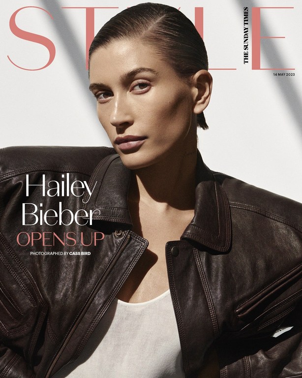 Magazine cover featuring a portrait of Hailey Bieber in a dark brown leather jacket, styled with slicked-back hair and a neutral makeup look.