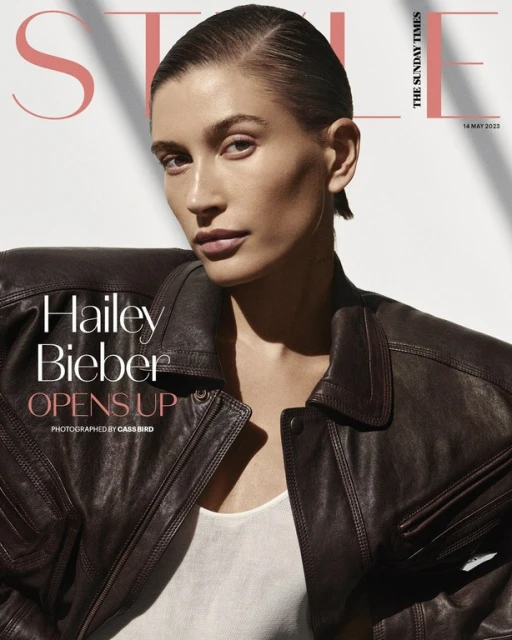 Magazine cover featuring a portrait of Hailey Bieber in a dark brown leather jacket, styled with slicked-back hair and a neutral makeup look.