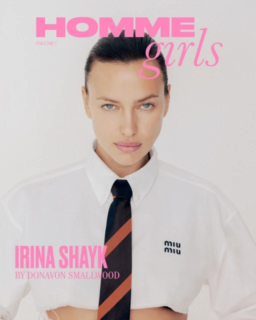 Close-up of Irina Shayk on a magazine cover, wearing a white shirt and tie, with pink magazine text against a bright neutral backdrop.