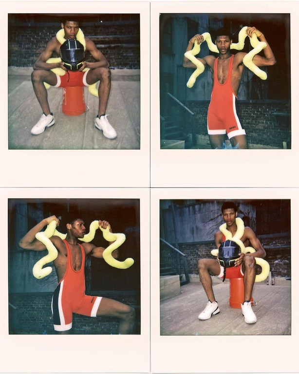 Four Polaroid photos of a man in a red wrestling uniform posing with a helmet and a yellow snake toy, set against an urban background.