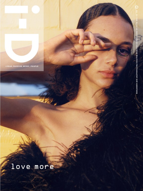 Magazine cover featuring a young adult woman with dark hair, partially covering her face with her hand, and wearing a black feather boa.