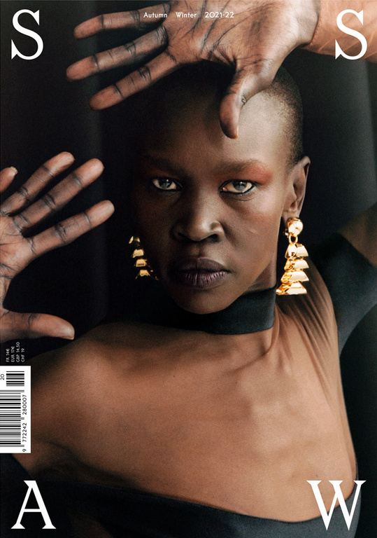 Fashion magazine cover featuring a striking Black woman with short hair, wearing large gold earrings, posing against a dark backdrop.