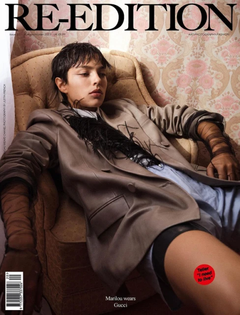 Magazine cover featuring a person reclining in an armchair, wearing a blazer, with a wallpapered background and dominant text.