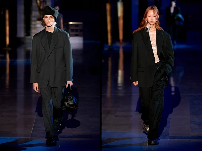 Two models walking a dark runway in oversized black blazers and trousers, styled by casting director Angus Munro.