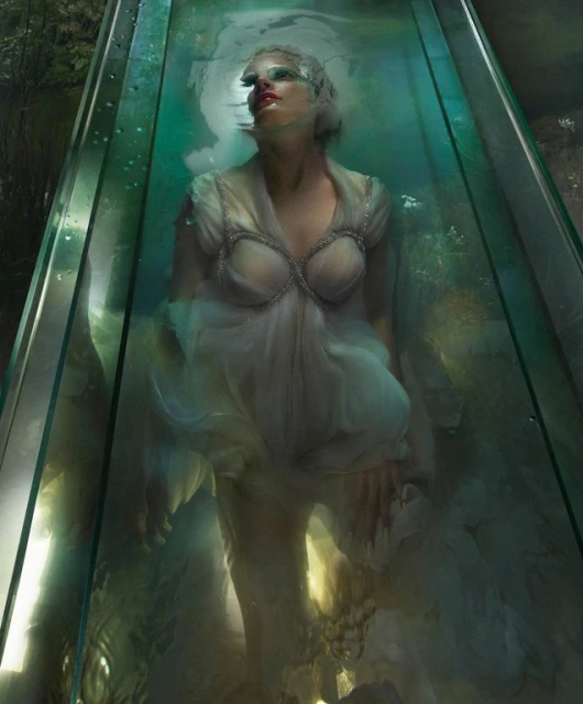 Artistic fashion portrait of a woman submerged in water, wearing a white dress, captured at eye-level in an outdoor setting with natural light.