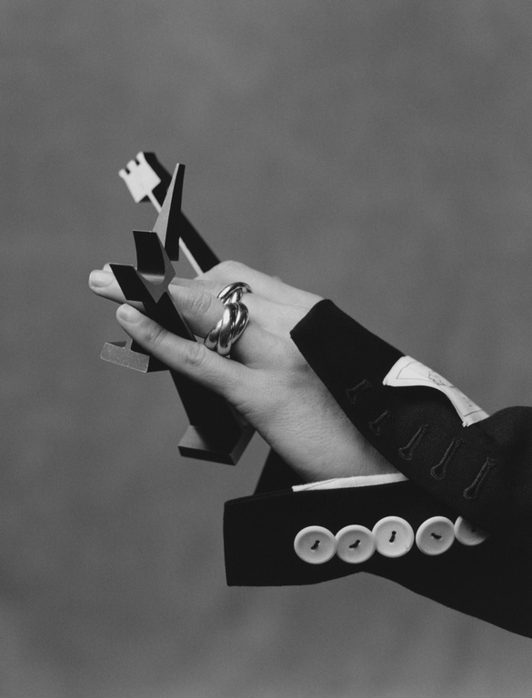 Elegant jewellery shoot in grayscale featuring a hand holding a modern geometric sculpture, accessorised with a statement silver ring.