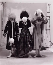 Three models wearing textured hats and coats holding white spherical props in a studio setup by Miguel Bento