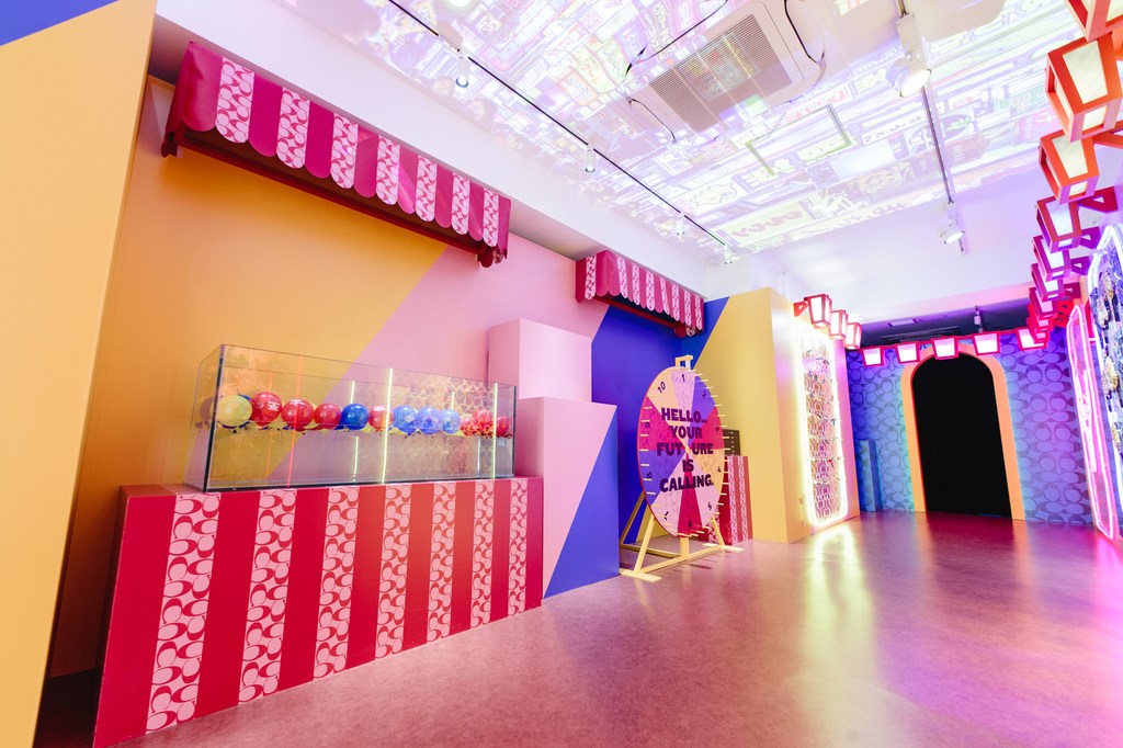 Indoor shot featuring a vibrant pop-up space with colorful geometric patterns, awning-style decorations, and playful installations.
