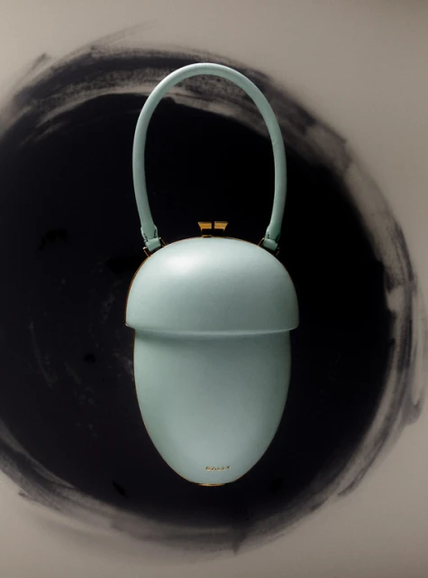 Light blue purse in an acorn shape with a curved handle and gold accents. The background features a circular, dark brushstroke pattern.