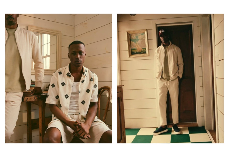 Two African-American men model light-colored jackets, shirts, and pants in a bright, traditionally styled interior with white wood paneling.