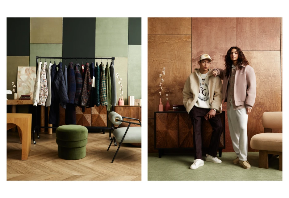 Two people model clothing in an interior setting with warm wood paneling and modern decor; clothing rack and furniture visible.