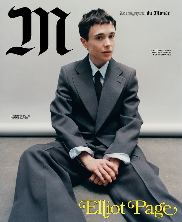 Elliot Page sits for the cover of Le Magazine du Monde, wearing a gray suit and tie against a light gray backdrop in a medium shot.