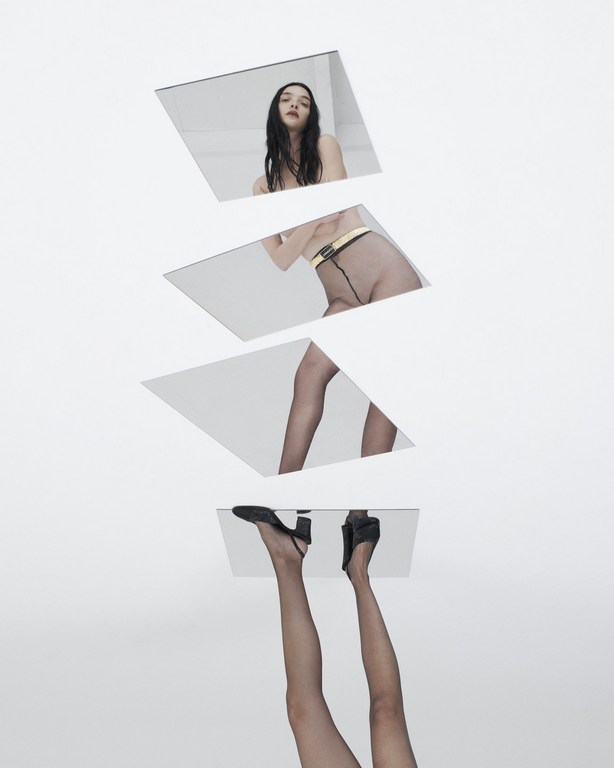 A young woman's reflection appears in vertically stacked mirrors, from head to toe, set against a clean, white backdrop in a studio shot.